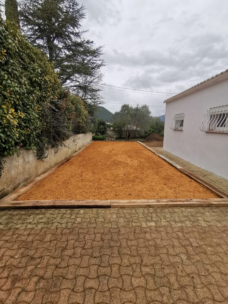 Terrain de pétanque ocre le long d'une maison provençale