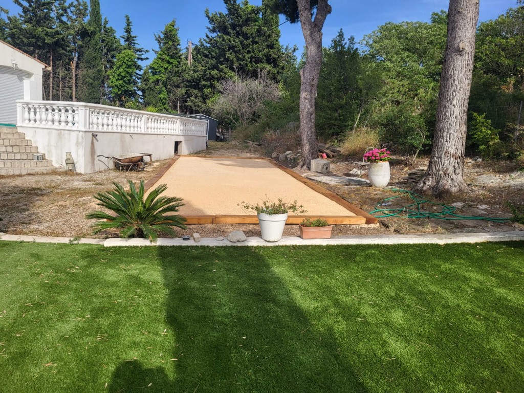 Terrain de pétanque dans un jardin paysager avec gazon synthétique